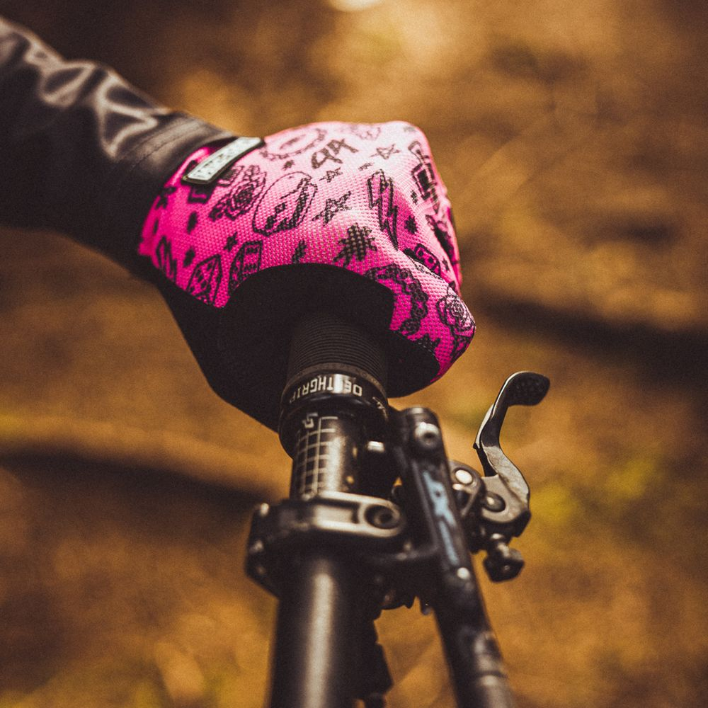 Eine Hand mit einem pinken Handschuh mit schwarzen Mustern greift nach dem Lenker eines Fahrrads.