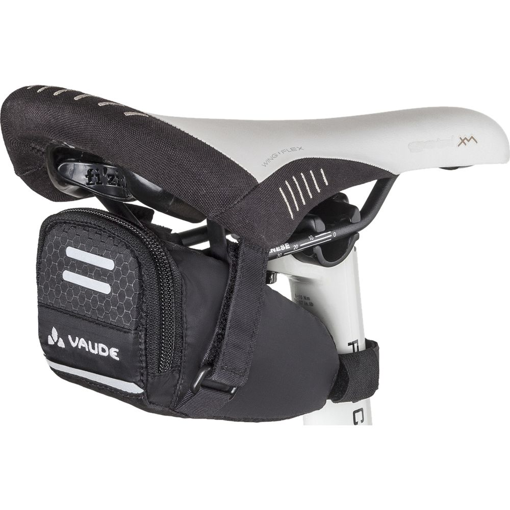 Une sacoche de selle Vaude noire à rayures réfléchissantes est fixée sous une selle de vélo.