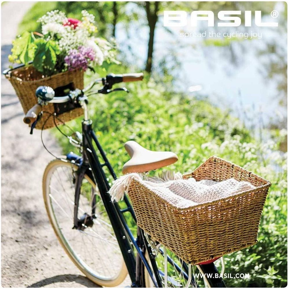 Ein Fahrrad mit Blumenkorb vorn und Textilienkorb hinten, am Ufer.