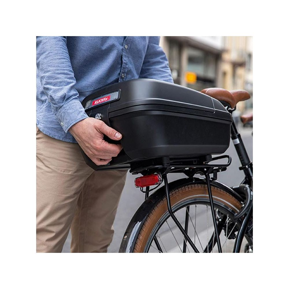 Mann montiert schwarzen KlickFix-Koffer auf Fahrrad-Gepäckträger.
