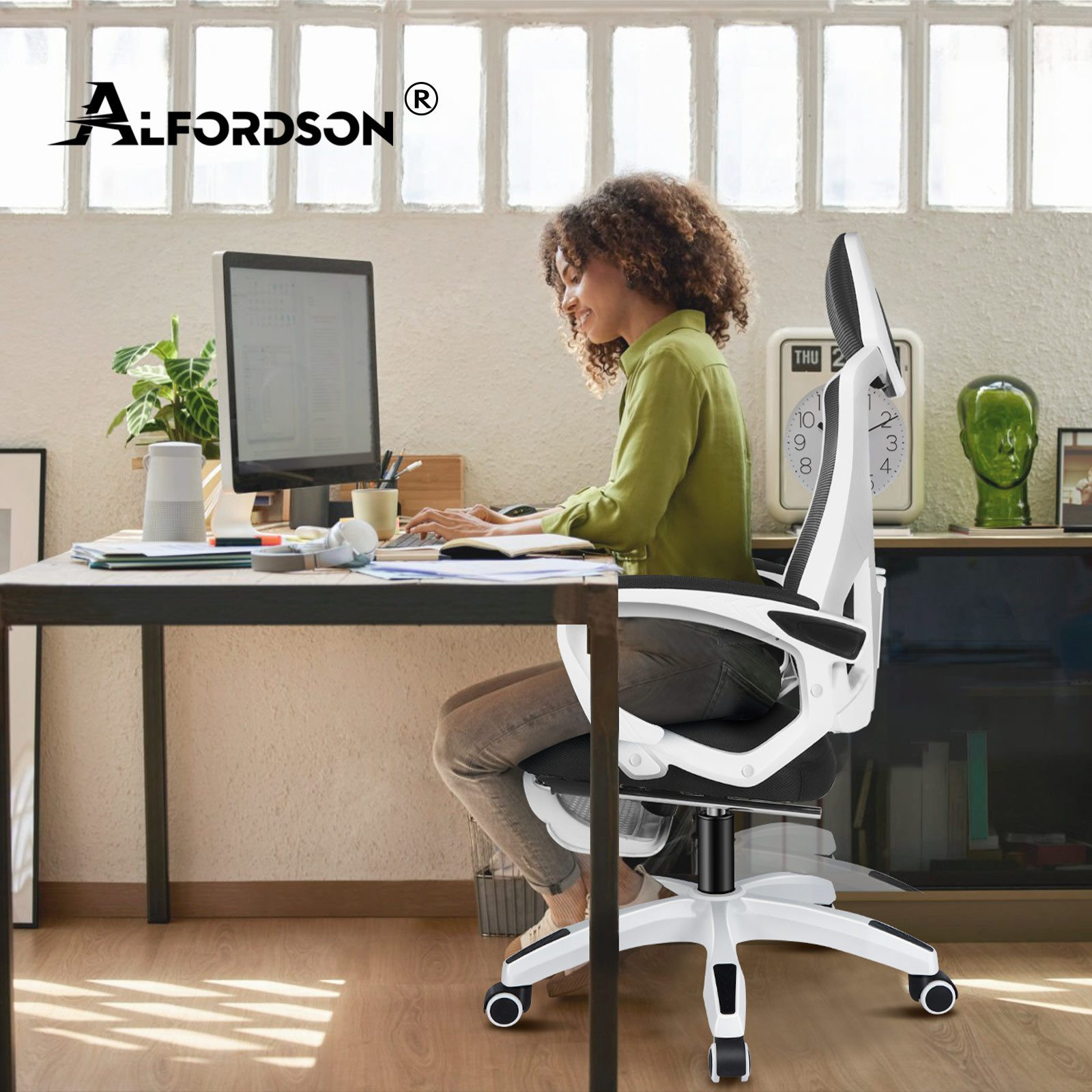 Eine Frau sitzt an einem Schreibtisch und arbeitet am Computer, ein Bürostuhl.