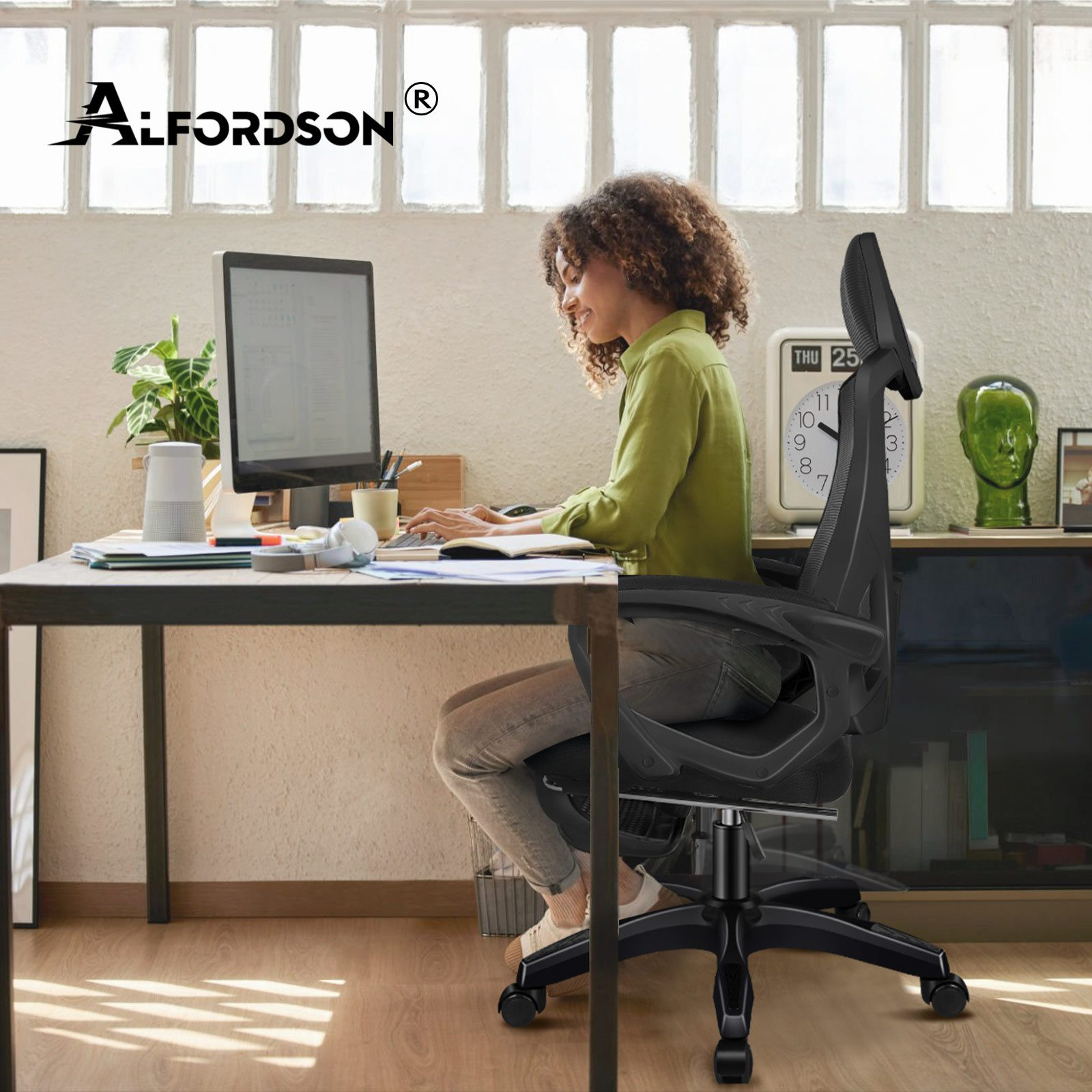 Frau arbeitet am Computer in einem Bürostuhl vor einem Fenster.