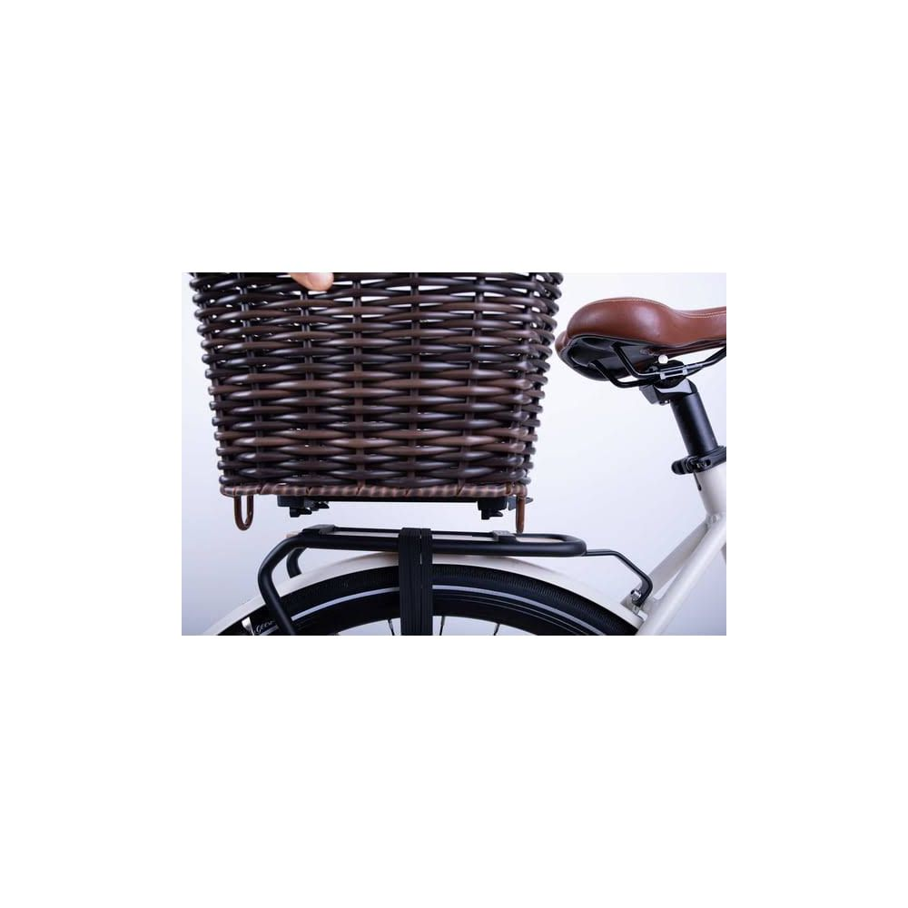 Una cesta de mimbre marrón está montada en una bicicleta blanca. Se ve parte de una mano.