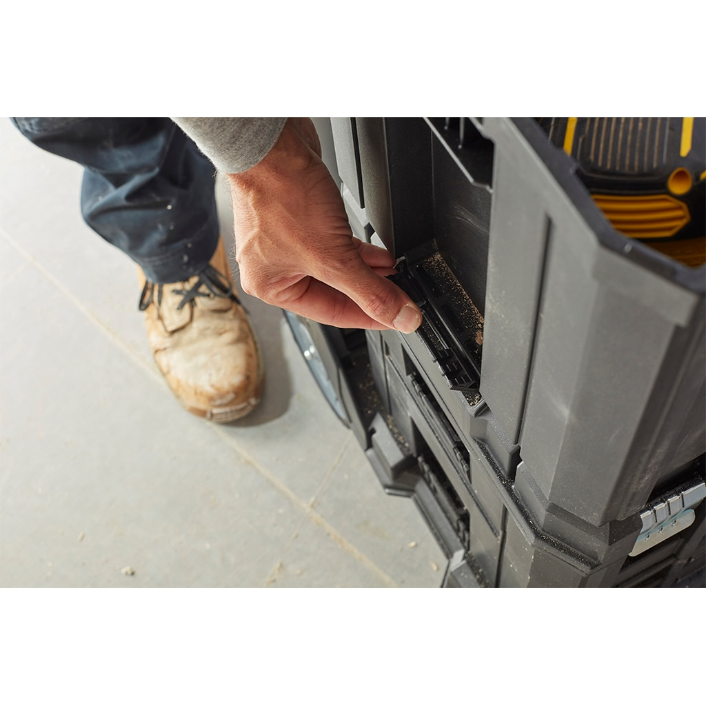 Hand bedient schwarzen Werkzeugkasten-Verschluss. Braune Schuhe und Jeans.