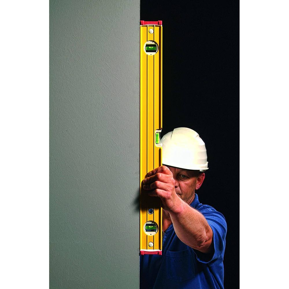Mann mit weißem Helm prüft Wand mit Wasserwaage.