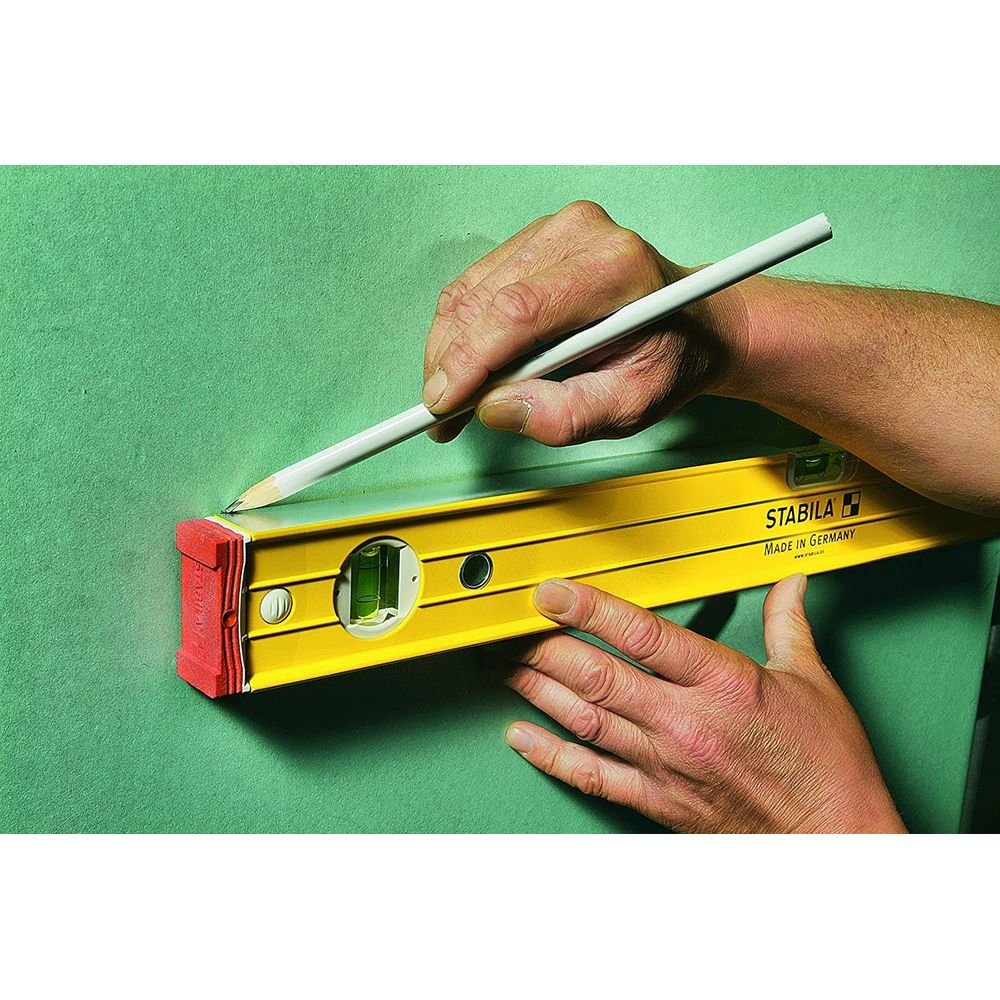 Eine Hand hält einen Bleistift und zeichnet eine Linie auf eine grüne Wand, während eine Wasserwaage gehalten wird.