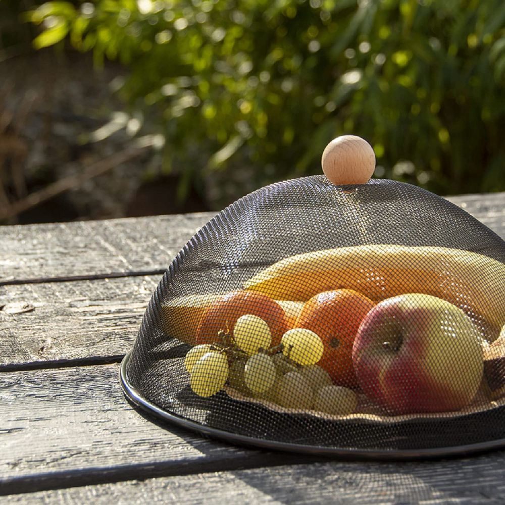 Obst unter einem Netzschutz auf einem Holztisch.