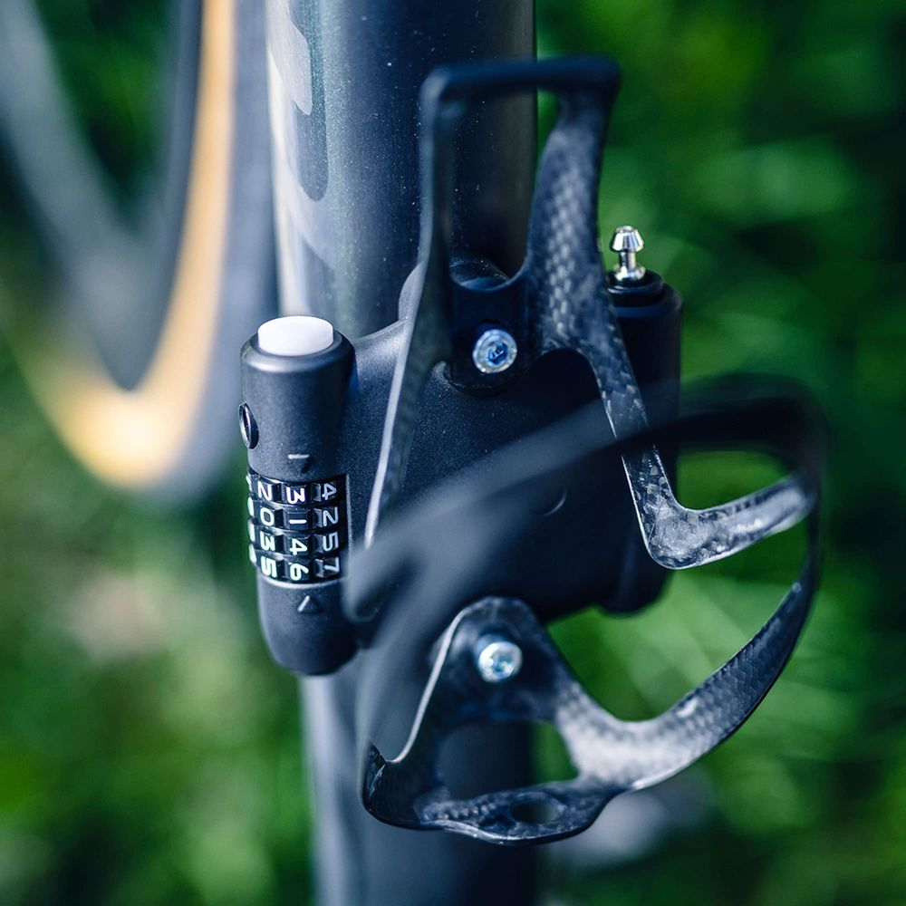 Nahaufnahme eines Fahrradschlosses mit Zahlenrädern und einer Carbon-Flaschenhalterung.
