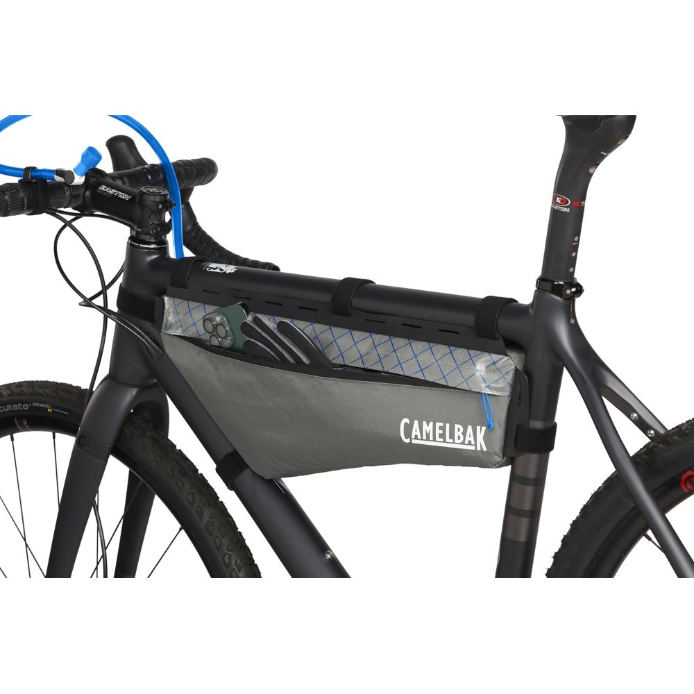 Grauer Rahmentasche mit "Camelbak"-Logo, gefüllt mit Handschuhen und Handy.