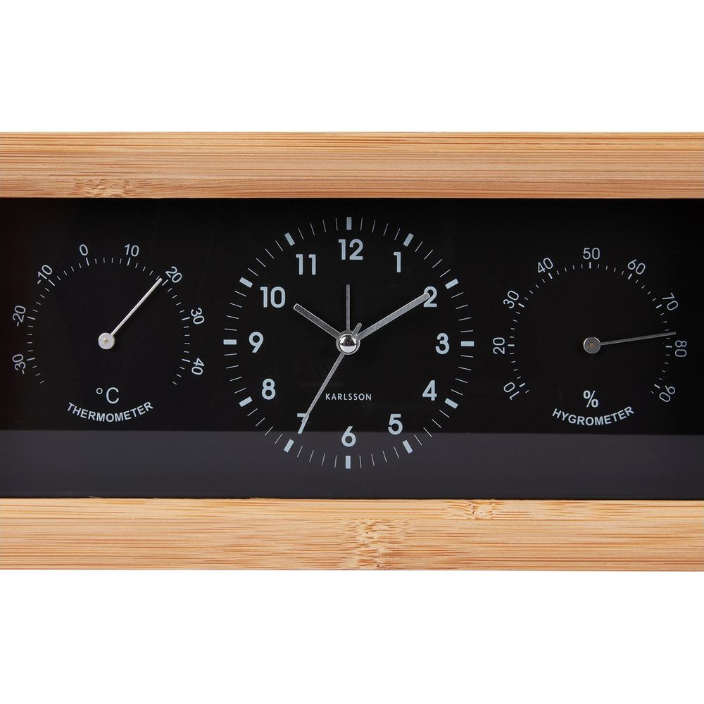 Une horloge Karlsson avec thermomètre et hygromètre dans un cadre en bois.