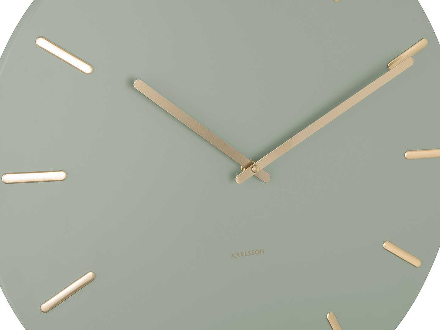 Eine graugrüne Wanduhr mit goldenen Zeigern und Strichmarkierungen.