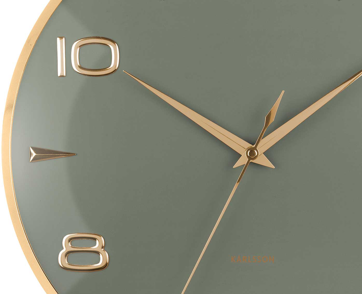 Gros plan d'une horloge murale avec aiguilles et marqueurs dorés sur un cadran vert sauge.