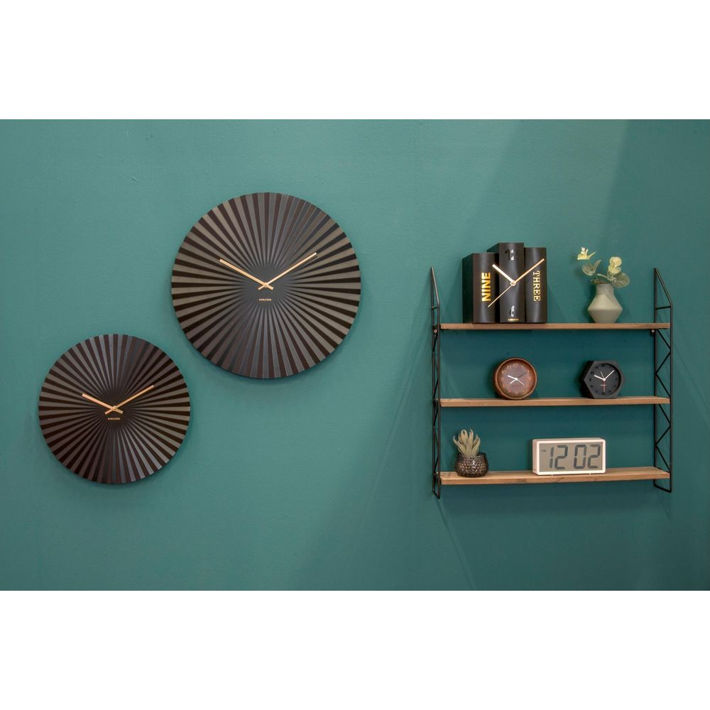 Deux horloges murales sombres et une étagère avec horloges, livres et plantes.