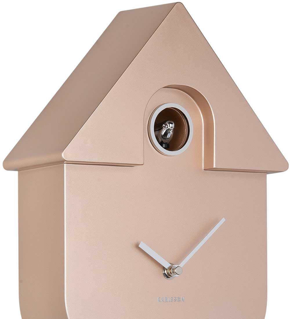 Horloge coucou dorée rose en forme de maison avec oiseau argenté et aiguilles blanches.