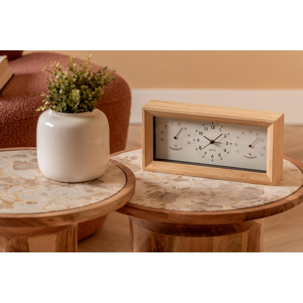 Une horloge en bois avec thermomètre et hygromètre est sur une table d'appoint.