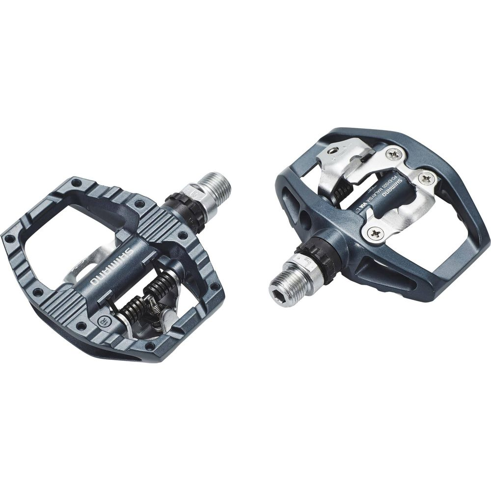 Zwei graue Shimano-Fahrradpedale, eines vorne links, eines hinten rechts.