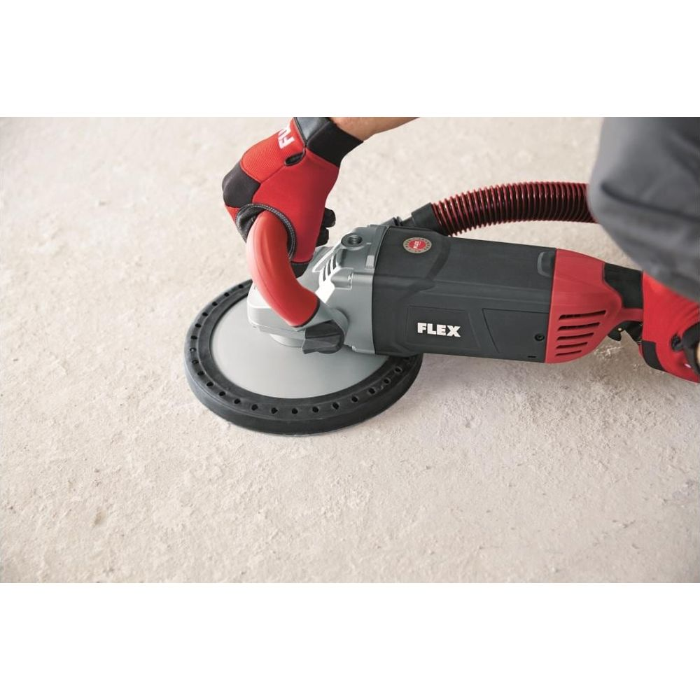 Une personne portant des gants rouges utilise une meuleuse FLEX sur du béton.