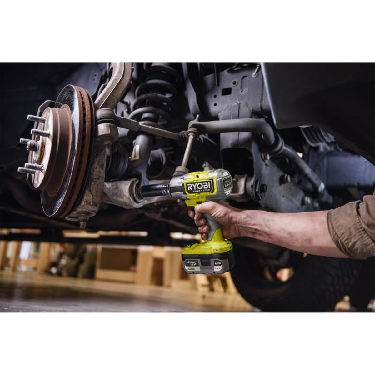 Eine Hand hält einen gelben Ryobi Schlagschrauber, der auf eine Radnabe eines Autos angewendet wird.