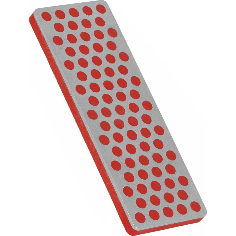 Une pierre à aiguiser rectangulaire avec bordure rouge et surface argentée à pois rouges.