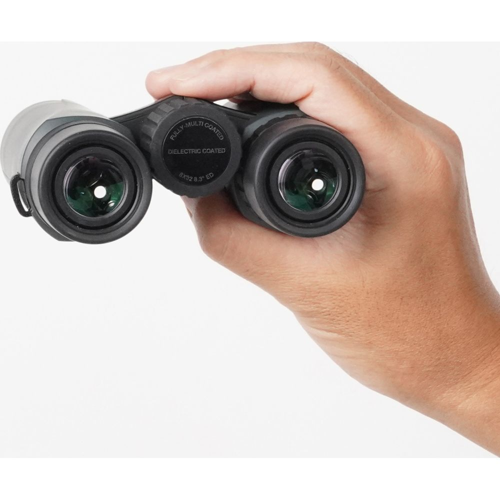 Una mano tiene un binocolo verde con l'etichetta 'FULLY-MULTI COATED'.