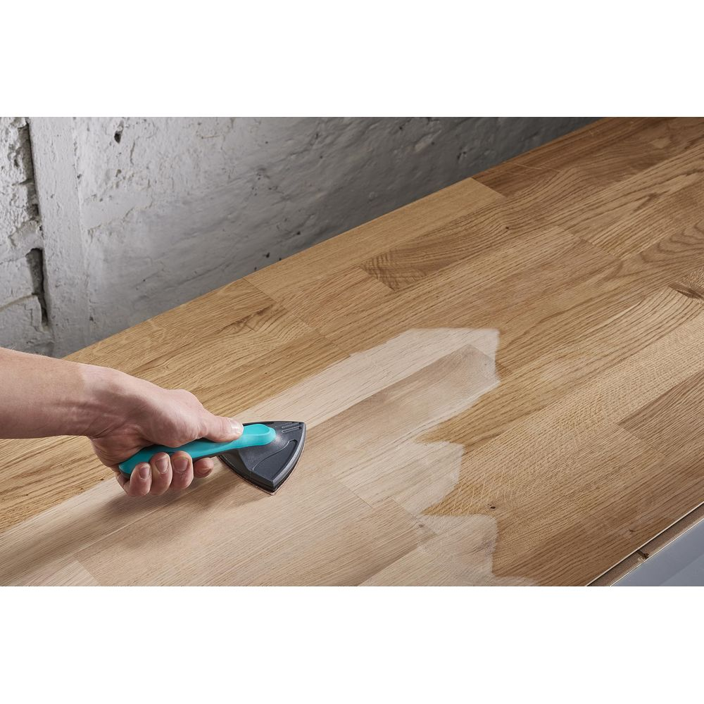 Une main utilise un outil pour nettoyer ou traiter une surface en bois.