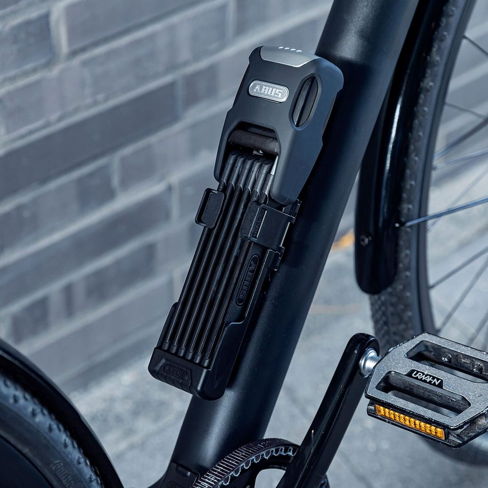 Ein schwarzes Fahrradschloss ist am schwarzen Fahrradrahmen befestigt.