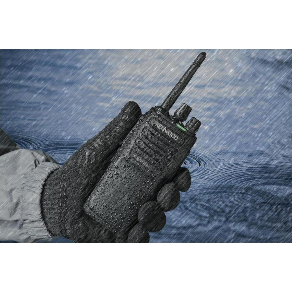 Eine Hand in einem schwarzen Handschuh hält ein schwarzes Kenwood Funkgerät im Regen.