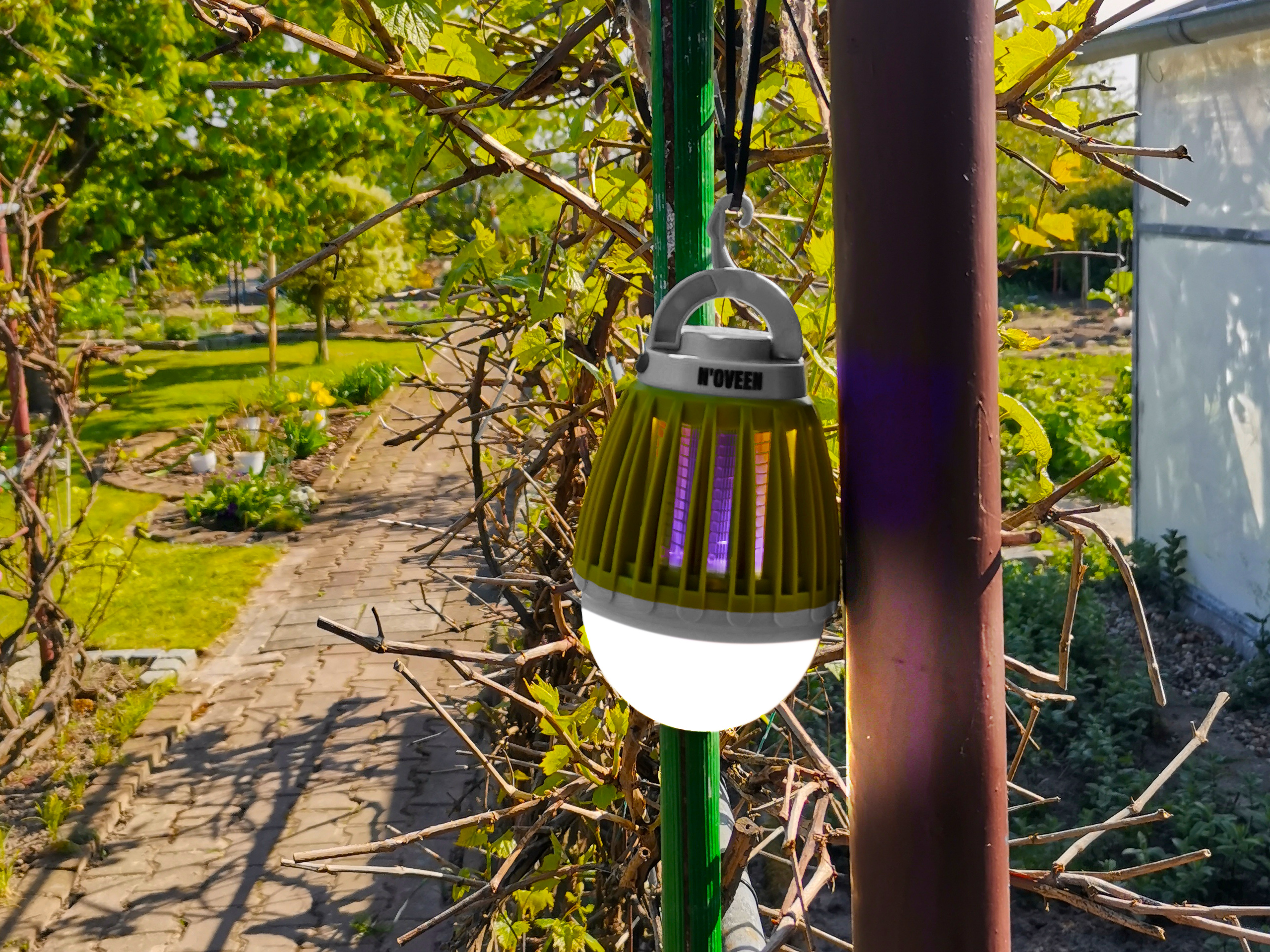 Żółta lampa owadobójcza wisi na słupku w ogrodzie.