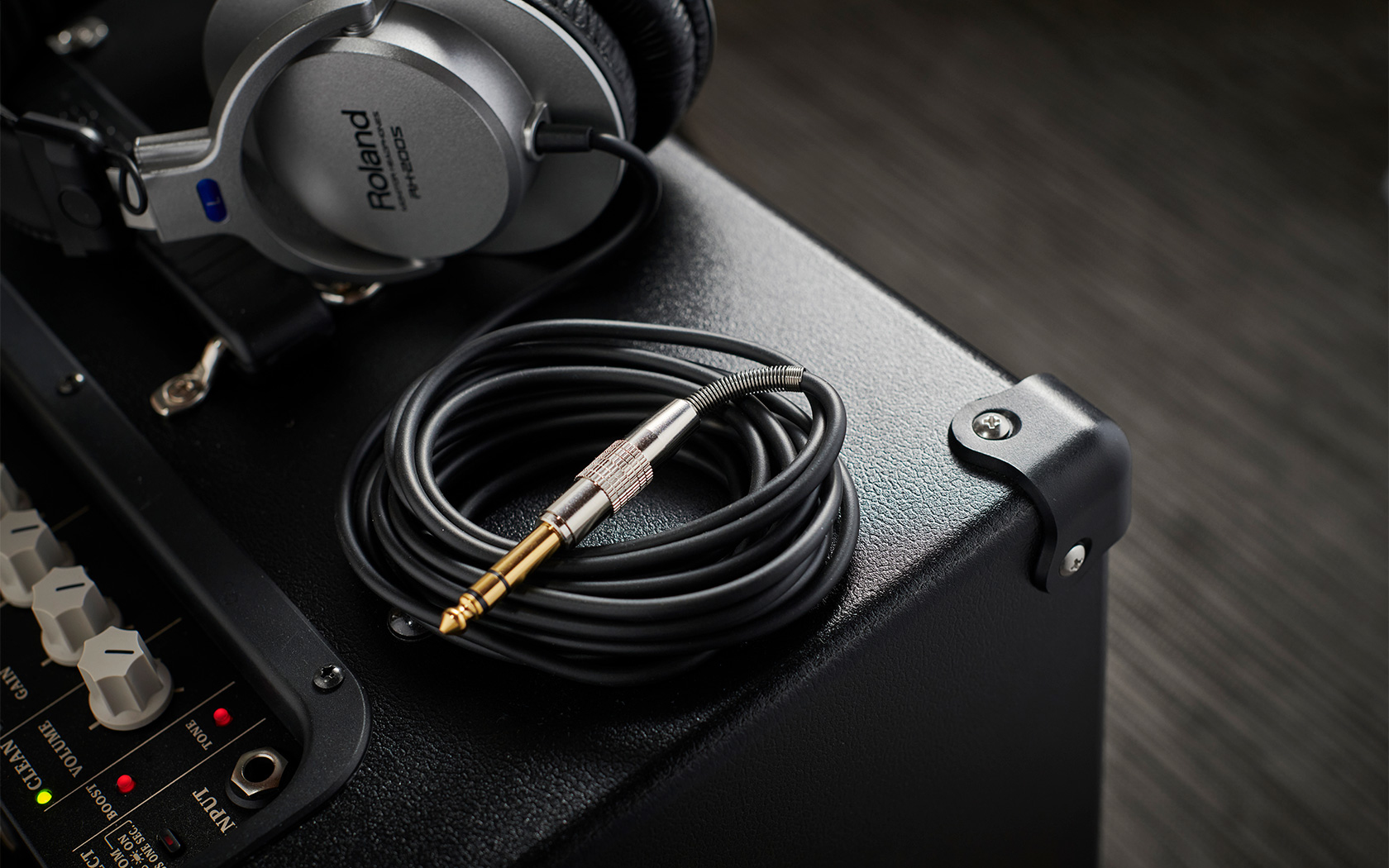 Un casque Roland et un câble reposent sur un amplificateur noir.