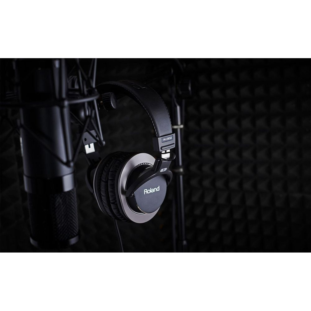 Casque Roland noir suspendu à côté d'un microphone devant des murs insonorisés.