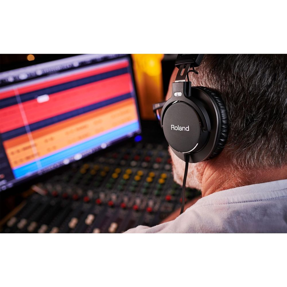 Homme avec casque Roland assis devant une console de mixage.