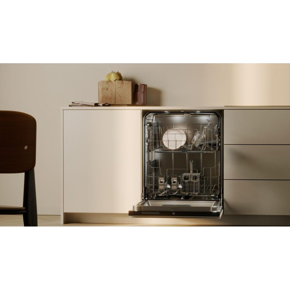 Lavastoviglie aperto con piatti, accanto una sedia e decorazione.