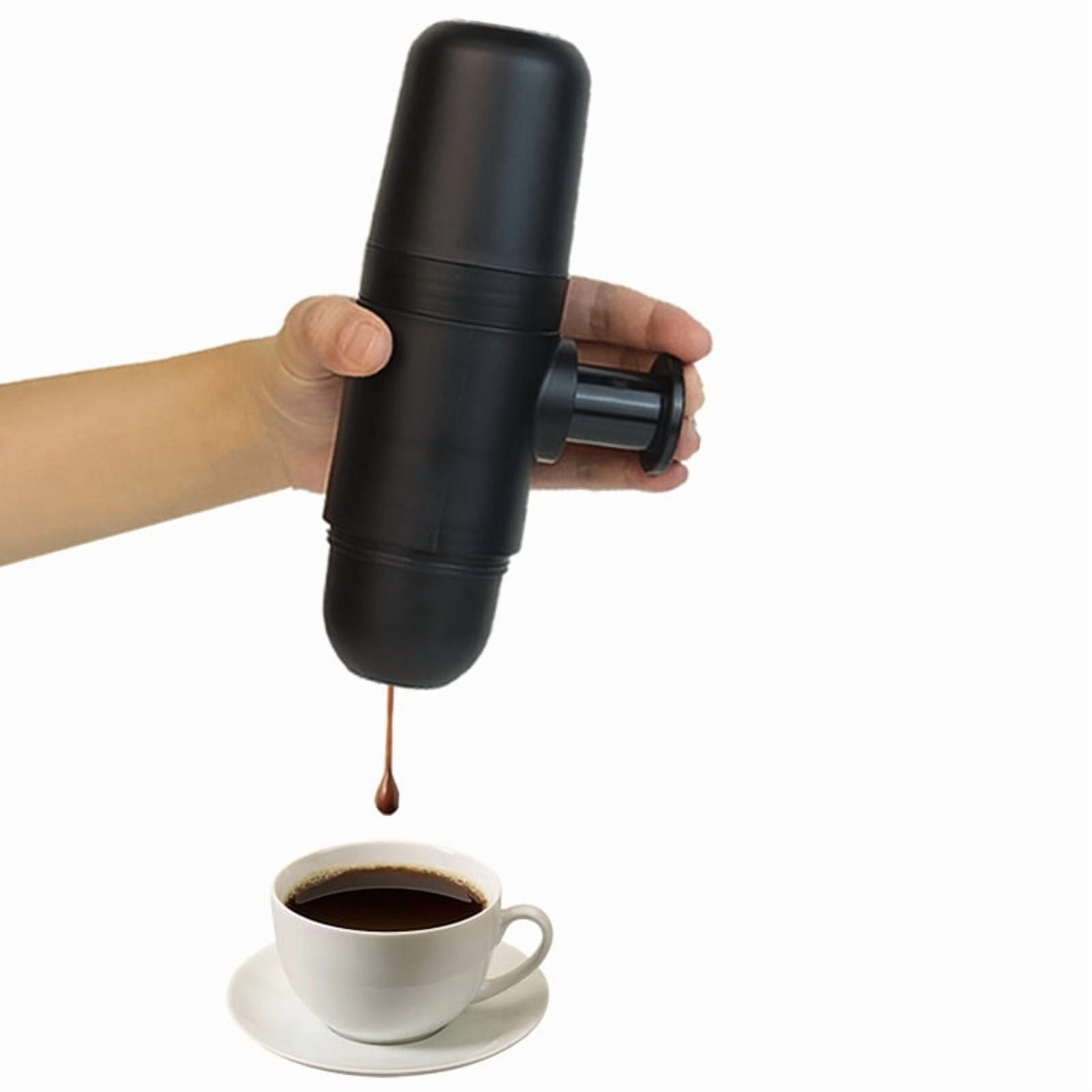 Eine Hand hält eine schwarze Espressomaschine, aus der Kaffee in eine weiße Tasse tropft.