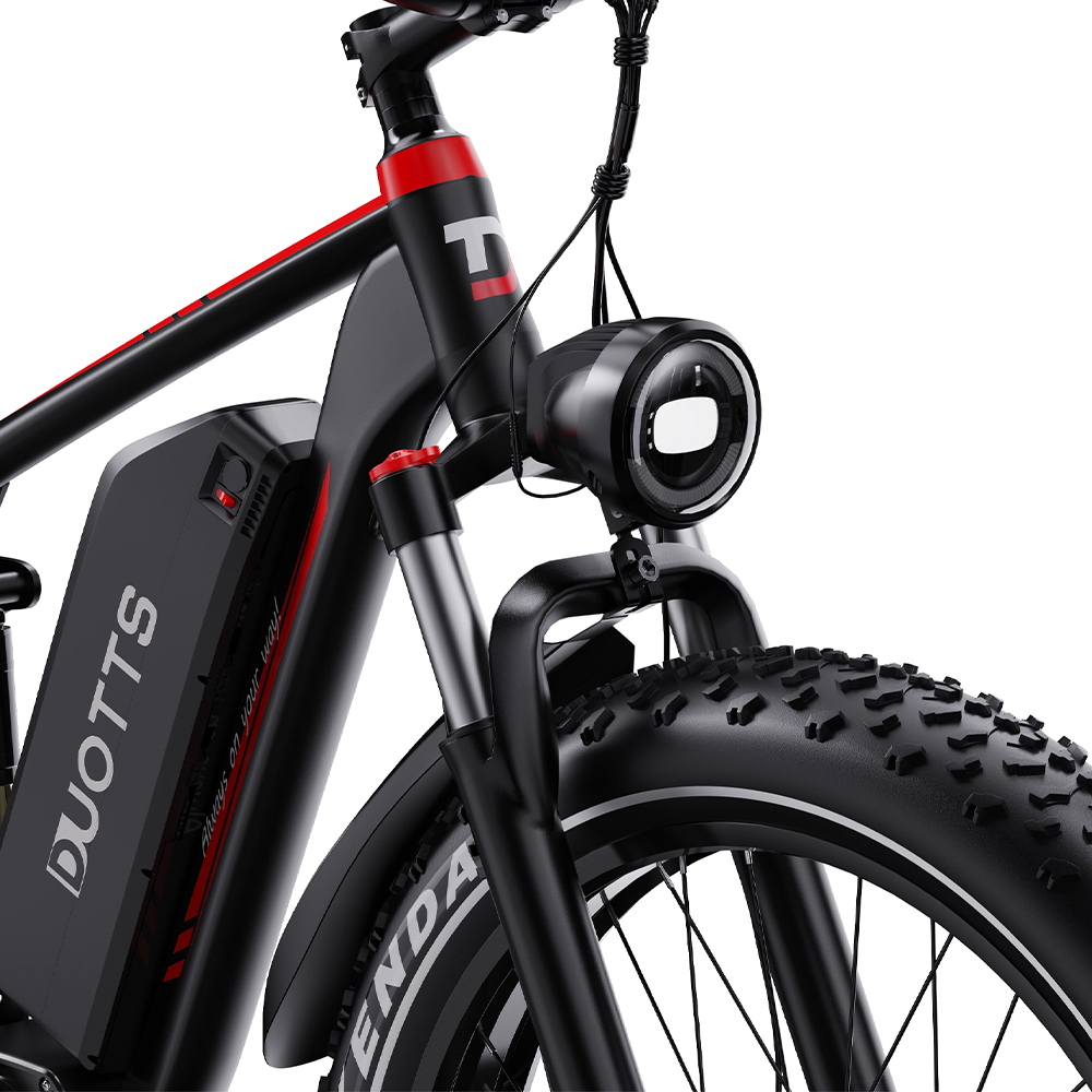 Bicicleta eléctrica negra con detalles rojos, luz frontal y neumático grueso.