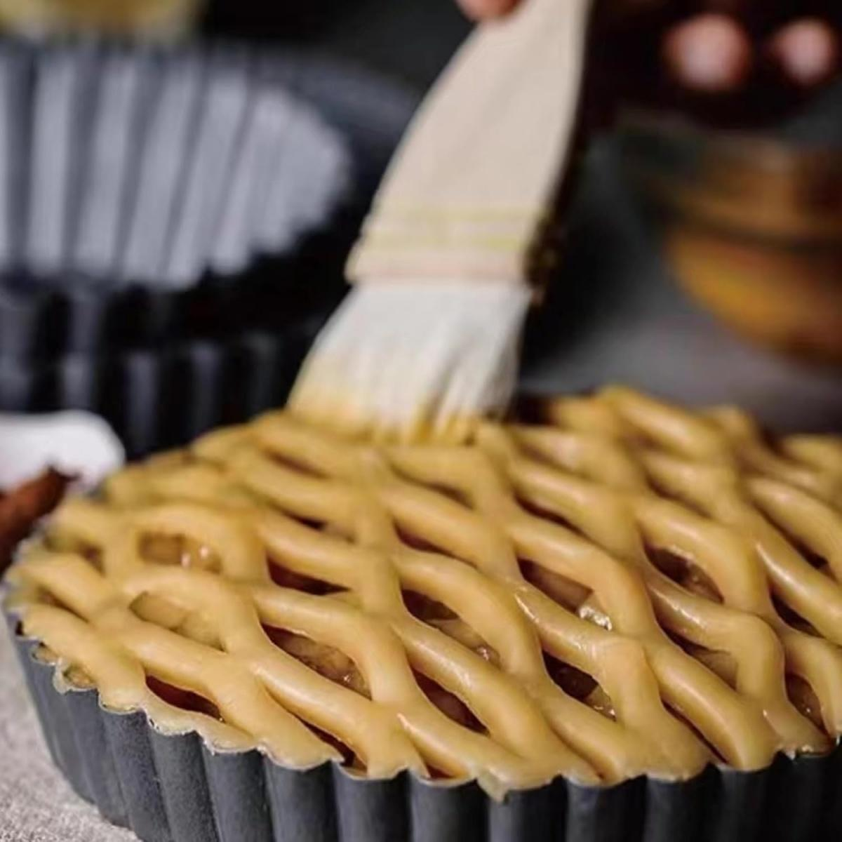 Ein Gittermuster-Kuchen wird mit einem Pinsel bestrichen.