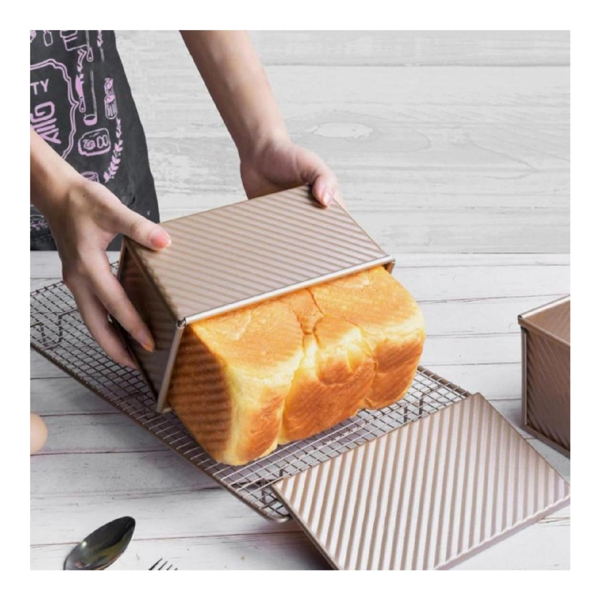 Goldbraunes Brot wird aus einer Pfanne gehoben, die auf einem Rost steht.