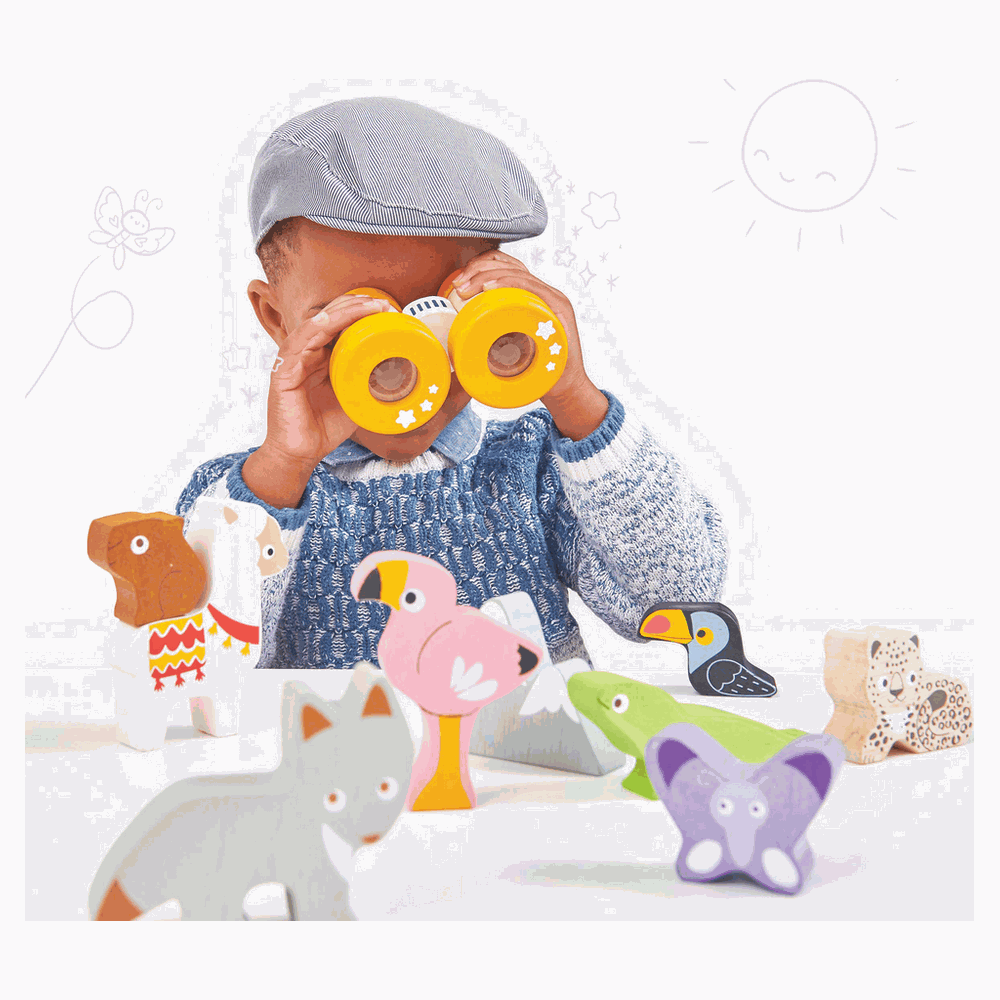Ein Junge mit Fernglas blickt auf Holztiere: Fuchs, Lama, Flamingo, Frosch, Papagei, Leopard.