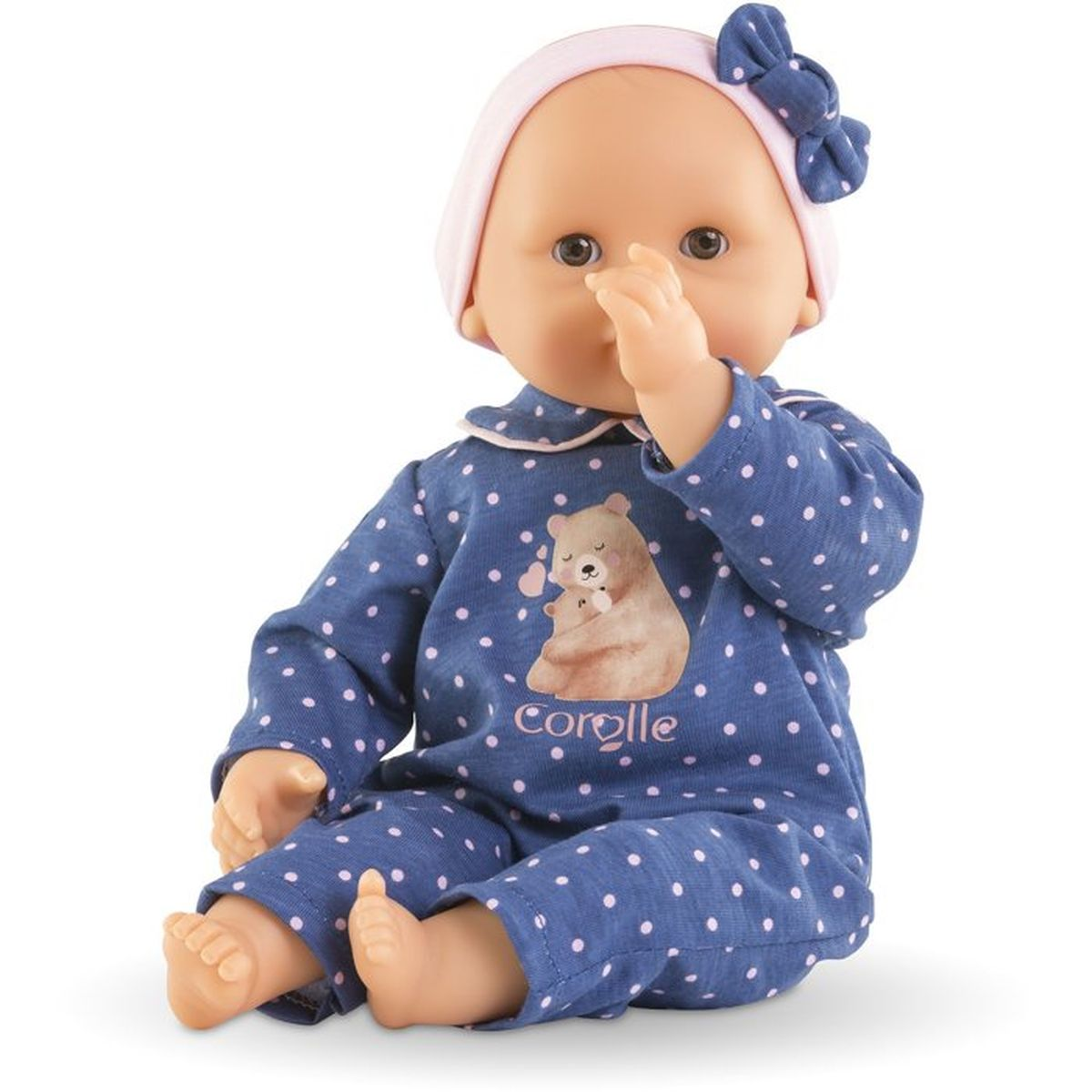 Eine Puppe in einem blauen Strampler mit rosa Tupfen und einem Bärenmotiv sitzt.