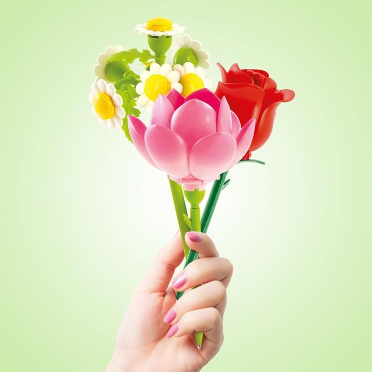 Eine Hand hält einen Strauß aus Plastikblumen: eine rosa Lotusblume, eine rote Rose und weiße Gänseblümchen.