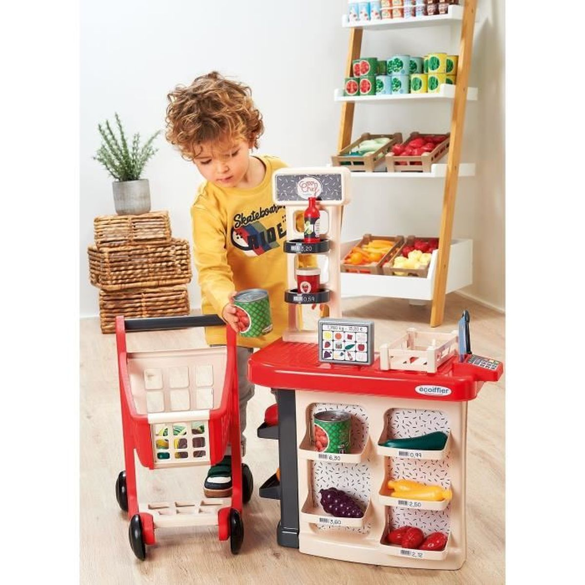 Un niño juega en una caja registradora de juguete con carrito y juguetes.