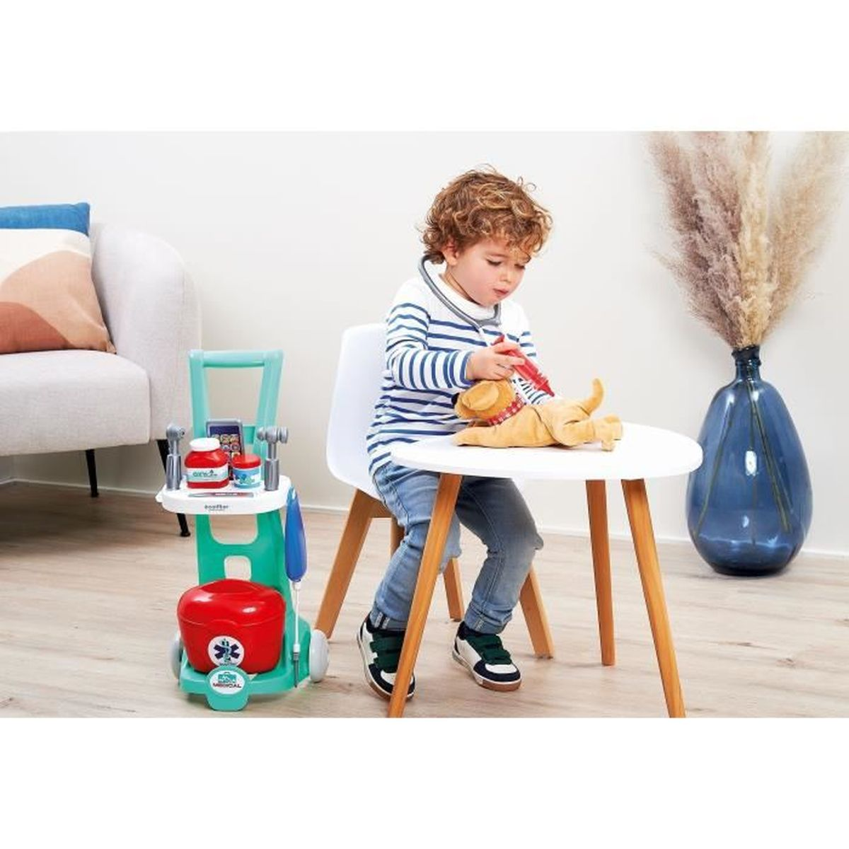Ein kleiner Junge im gestreiften Hemd spielt Arzt mit einem Spielzeughund auf einem Tisch.