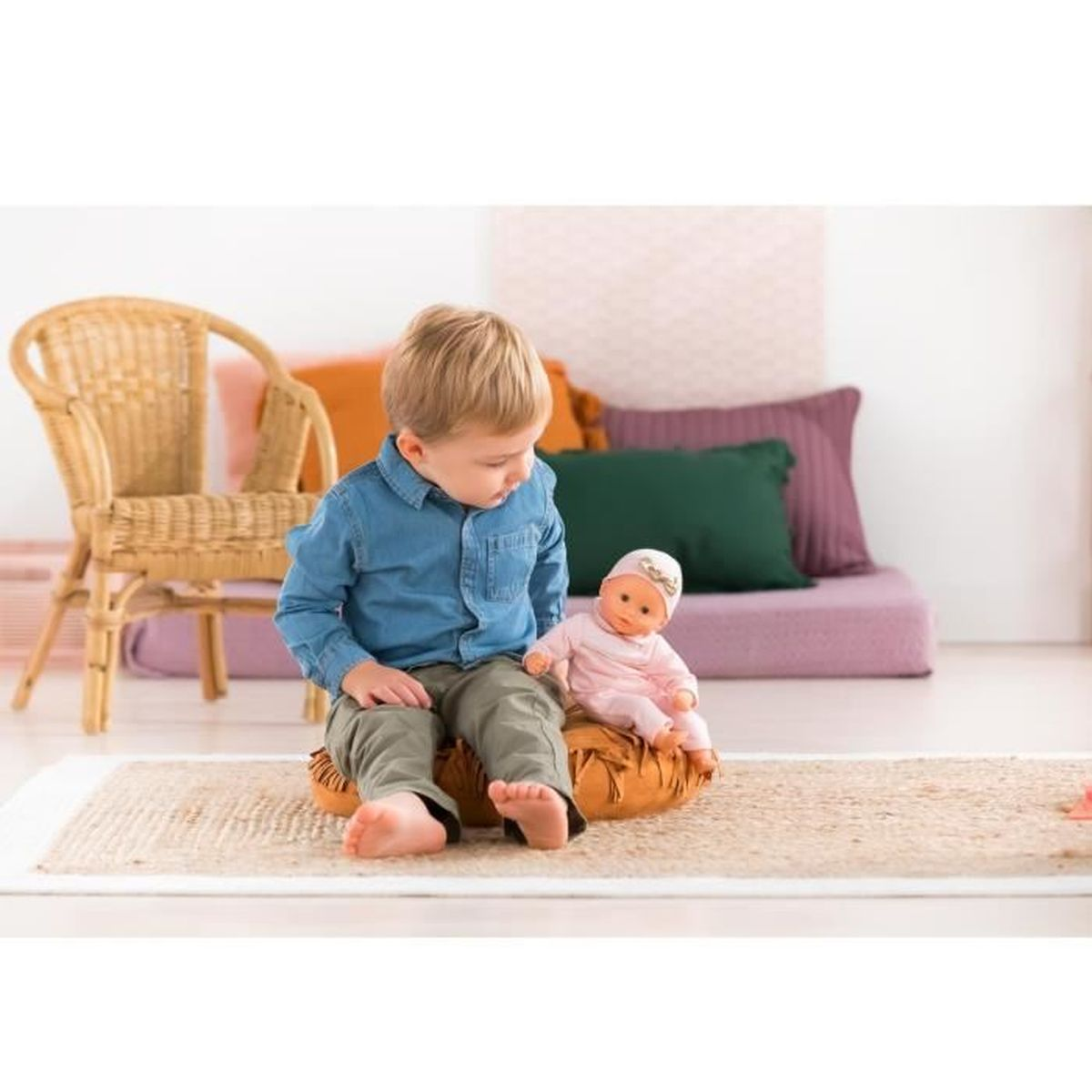 Ein kleiner Junge sitzt auf einem Kissen und spielt mit einer Puppe.