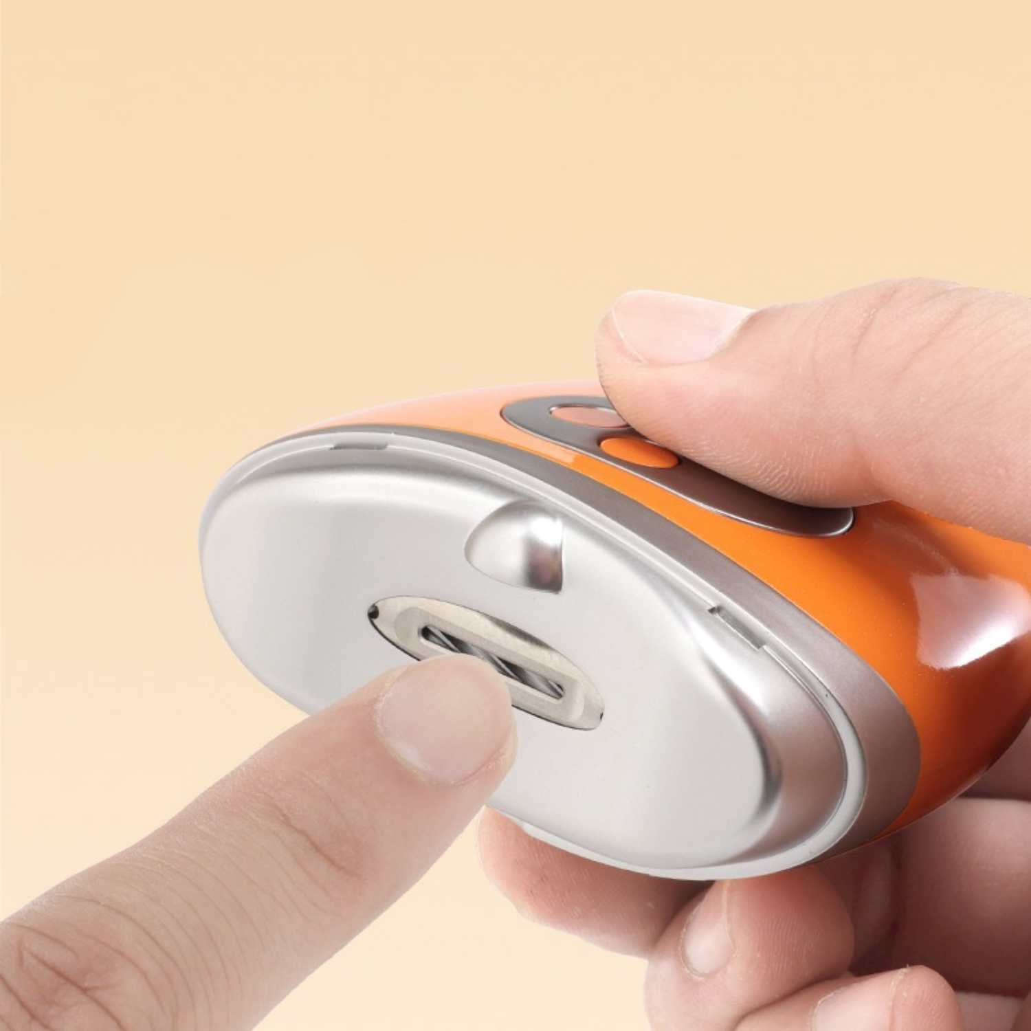 Eine Hand hält ein orange-silbernes Gerät, ein Finger drückt auf die silberne Oberfläche.