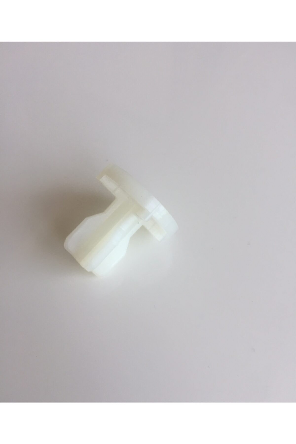 T şeklinde gövdesi ve konik ucu olan beyaz plastik parça.