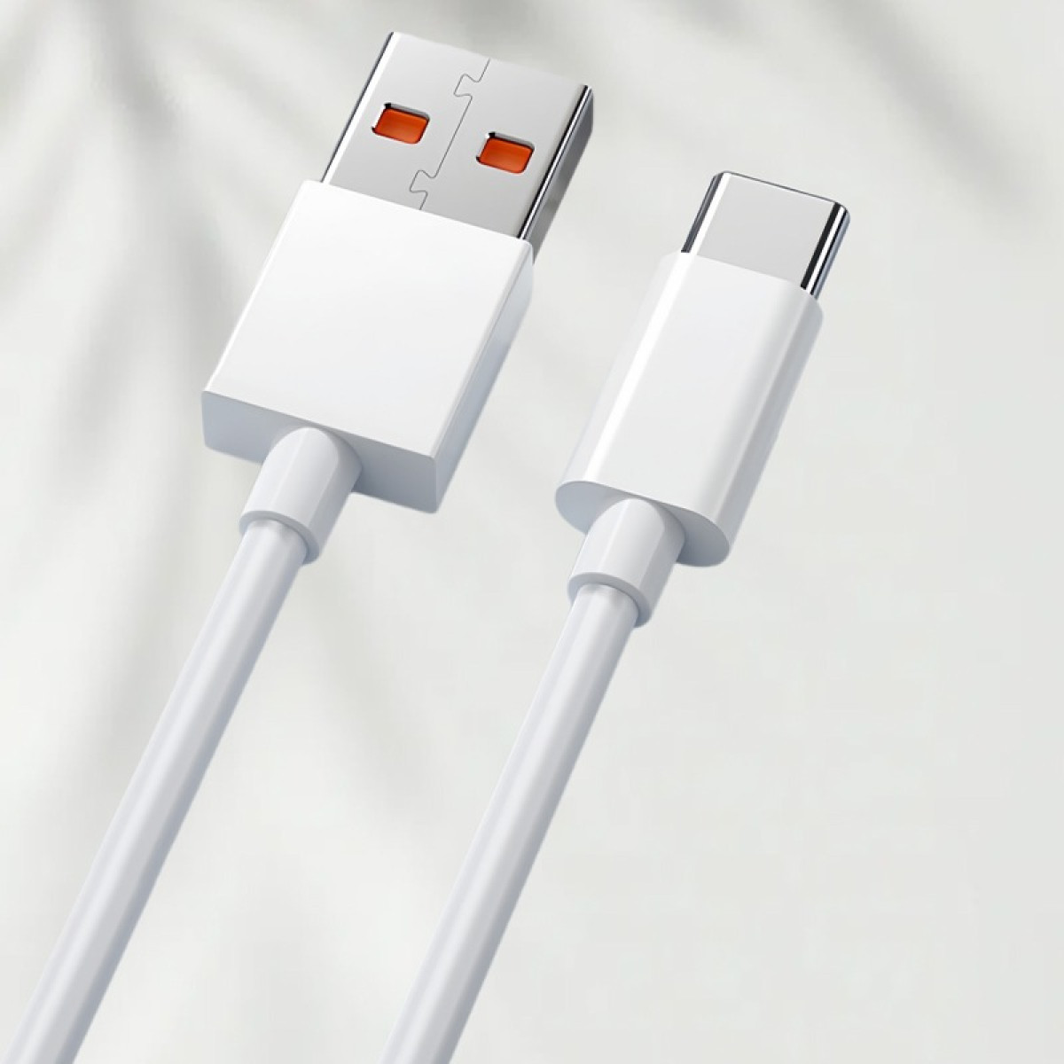 Un cavo da USB-A a USB-C bianco giace su uno sfondo chiaro e ombreggiato.