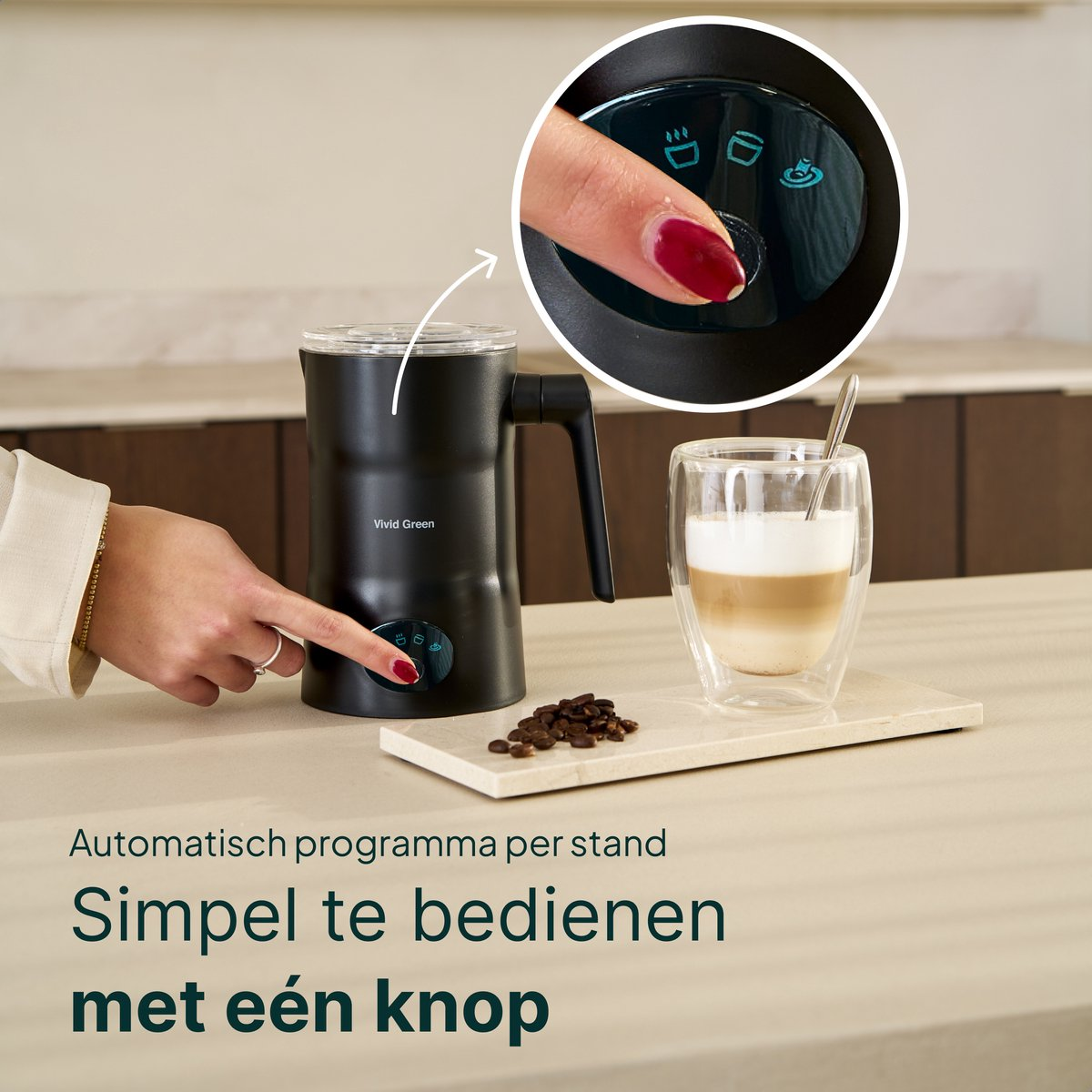 A hand presses a button on a black milk frother next to a latte macchiato.