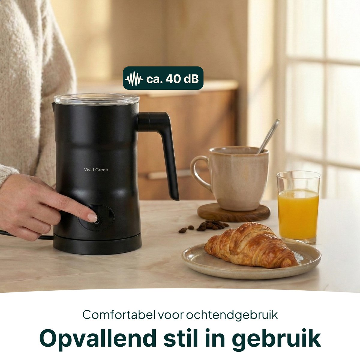 A black milk frother next to a mug and a croissant.
