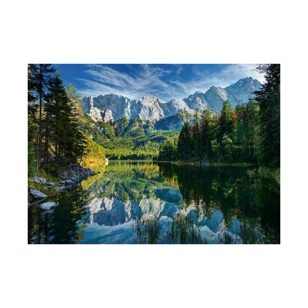 Spiegelglatte See mit Bergen und Wald im Hintergrund, blauer Himmel.