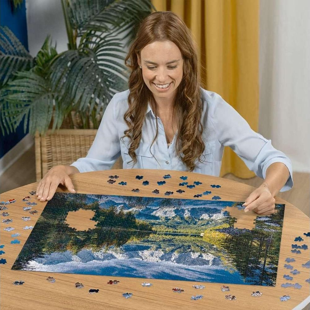 Frau löst ein Puzzle mit Bergsee-Motiv an einem Holztisch.