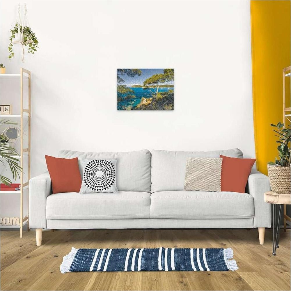 Ein Gemälde einer Küstenlandschaft mit Bäumen und blauem Wasser an der Wand.